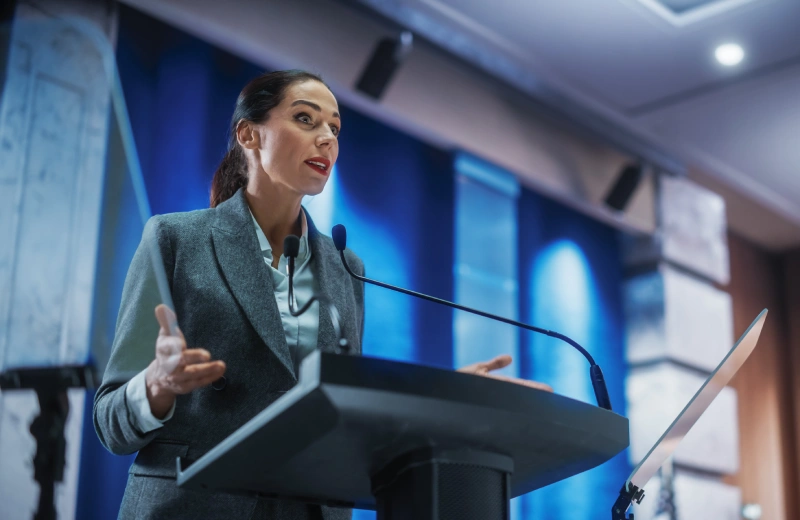 A woman is speaking at a podium in front of a microphone.